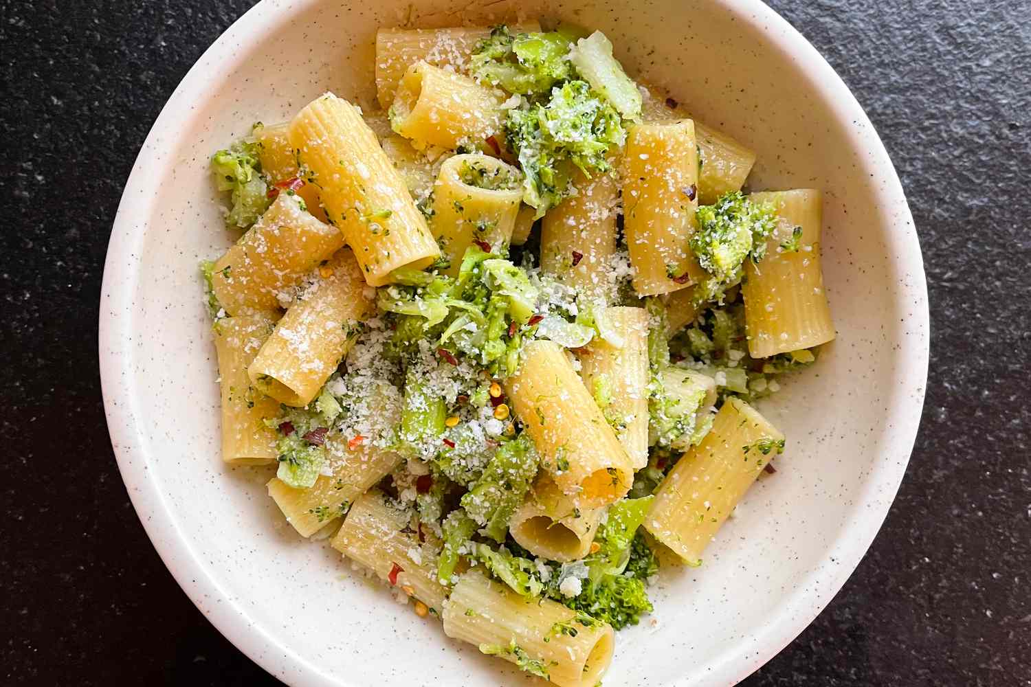 Overhead shot of a bowl of rigatoni pasta with broccoli and parmesan cheese