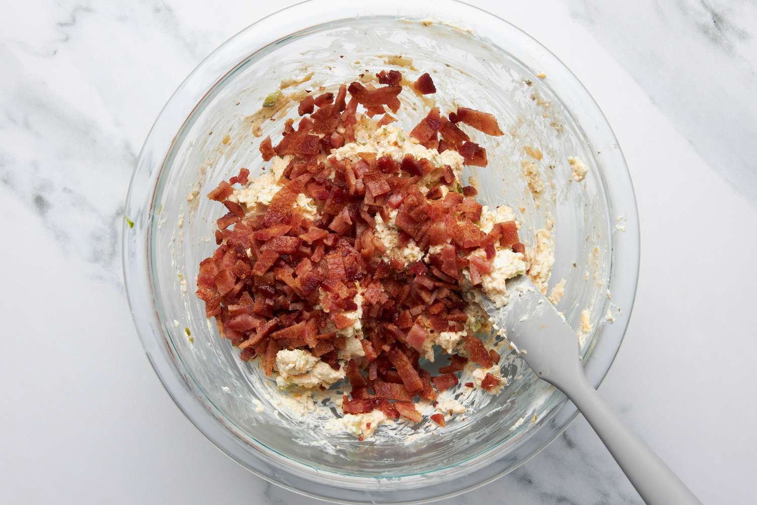 Sliced bacon added to bowl of jalapeÃ±o popper grilled cheese ingredients