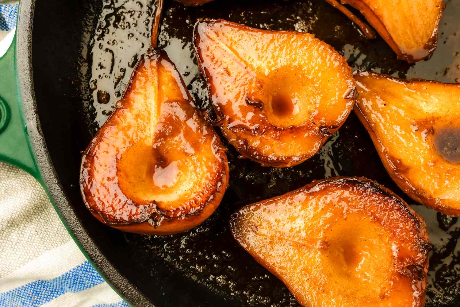 Halved pears cooked and glazed arranged in a cast iron skillet