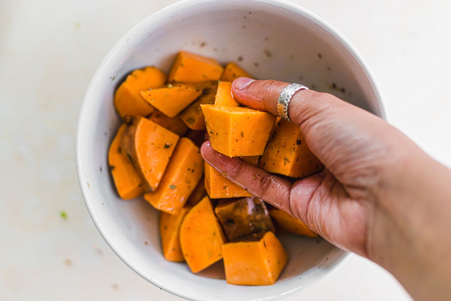 Hands holding olive oil and spiced sweet potatoes