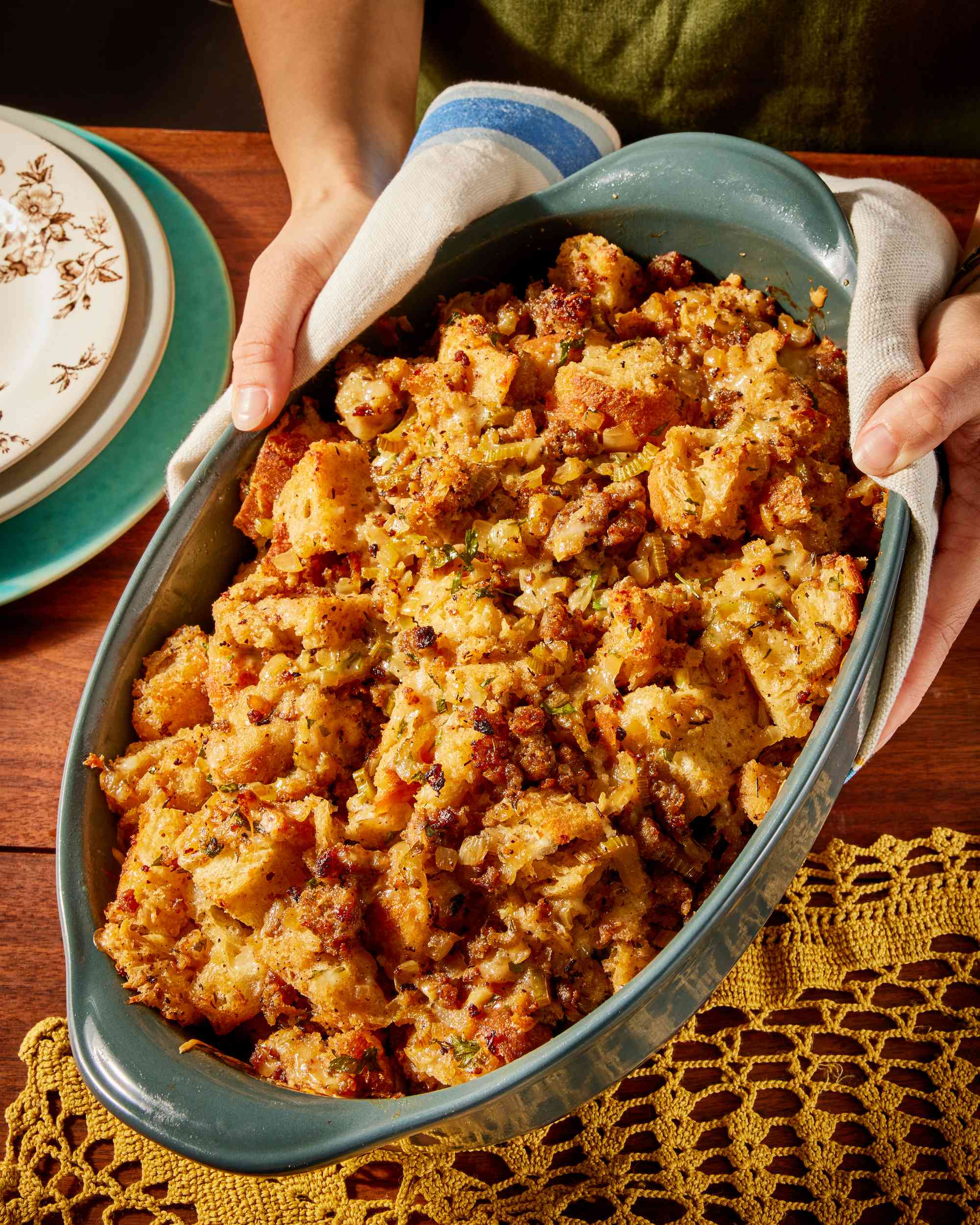 Hands placing a casserole dish of stuffing onto a table