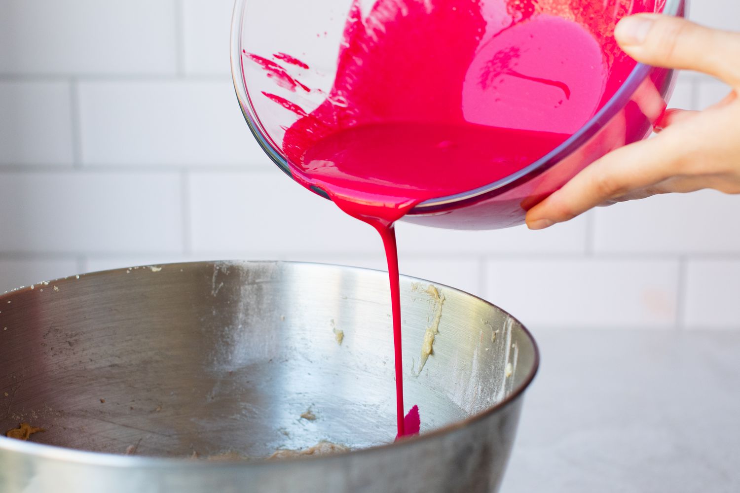 Adding red colored wet ingredients to the stand mixer bowl for the best red velvet cake recipe.