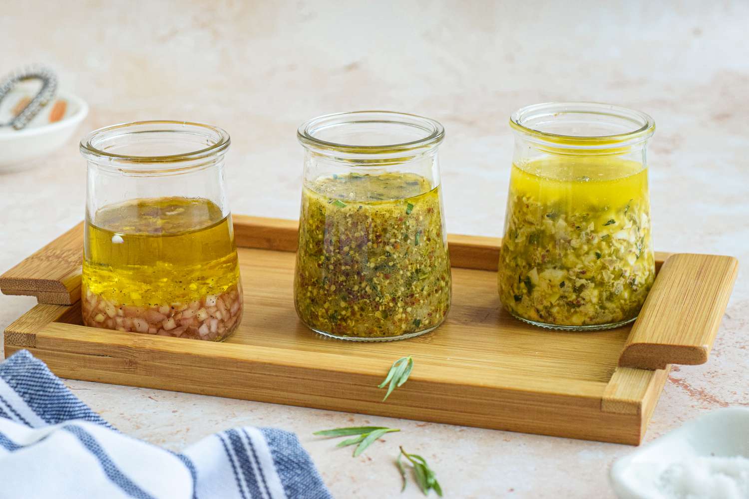 Three Jars of Vinaigrette (From Left to Right: Sherry-Shallot Vinaigrette, Tarragon-Mustard Vinaigrette, and Gribiche Vinaigrette) on a Wooden Tray
