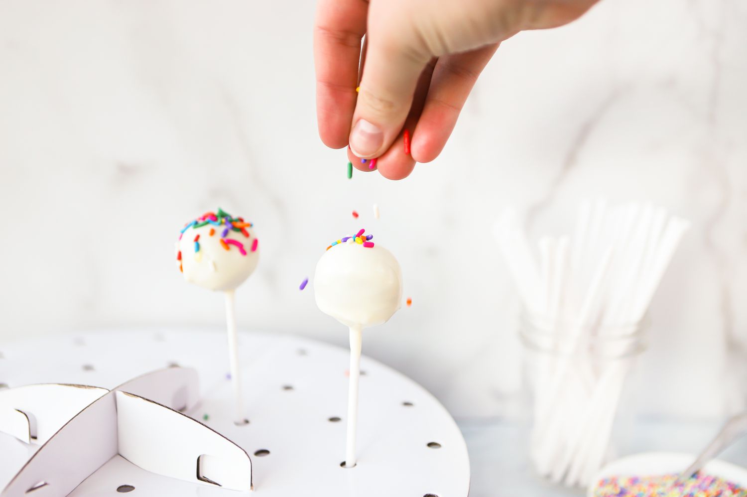 Sprinkles Added to Cake Pop Sitting on Tray with Holes 