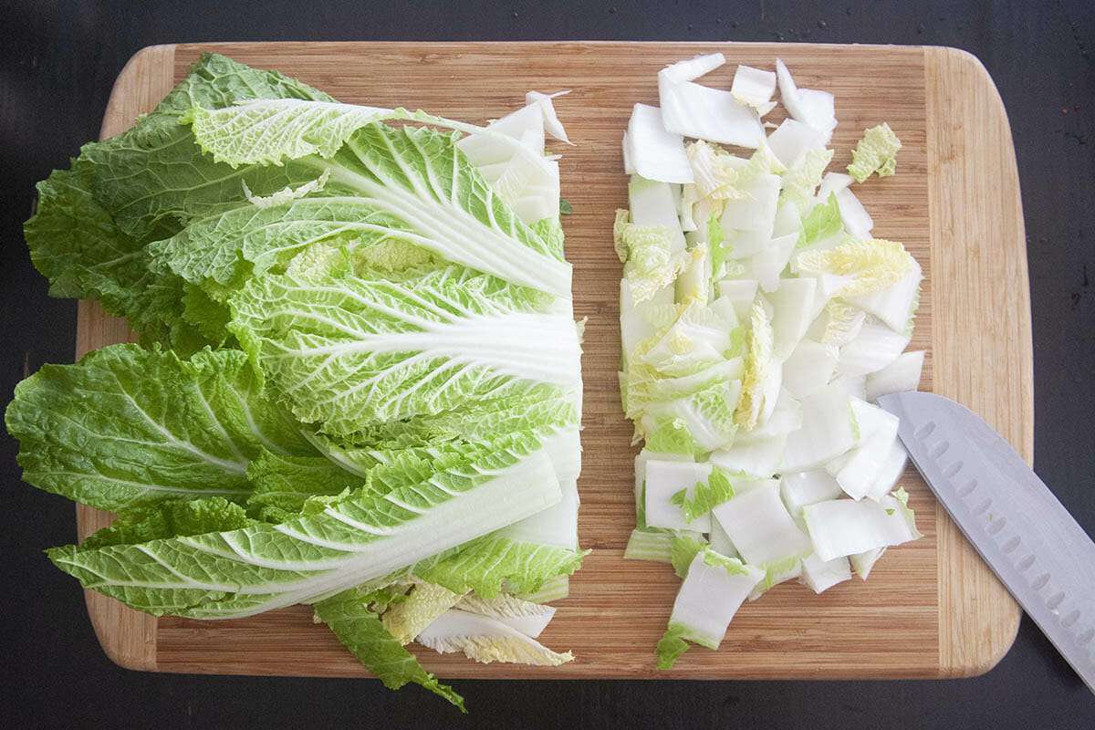 Napa cabbage being chopped on a cutting board for an easy homemade kimchi.