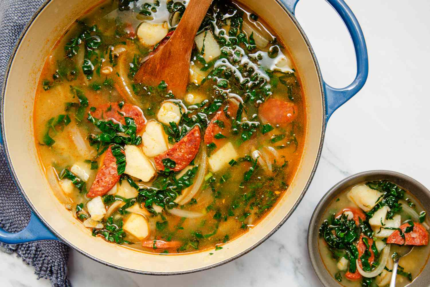 large pot of Caldo Verde (Portuguese Kale Soup) with a bowl of the soup next to it