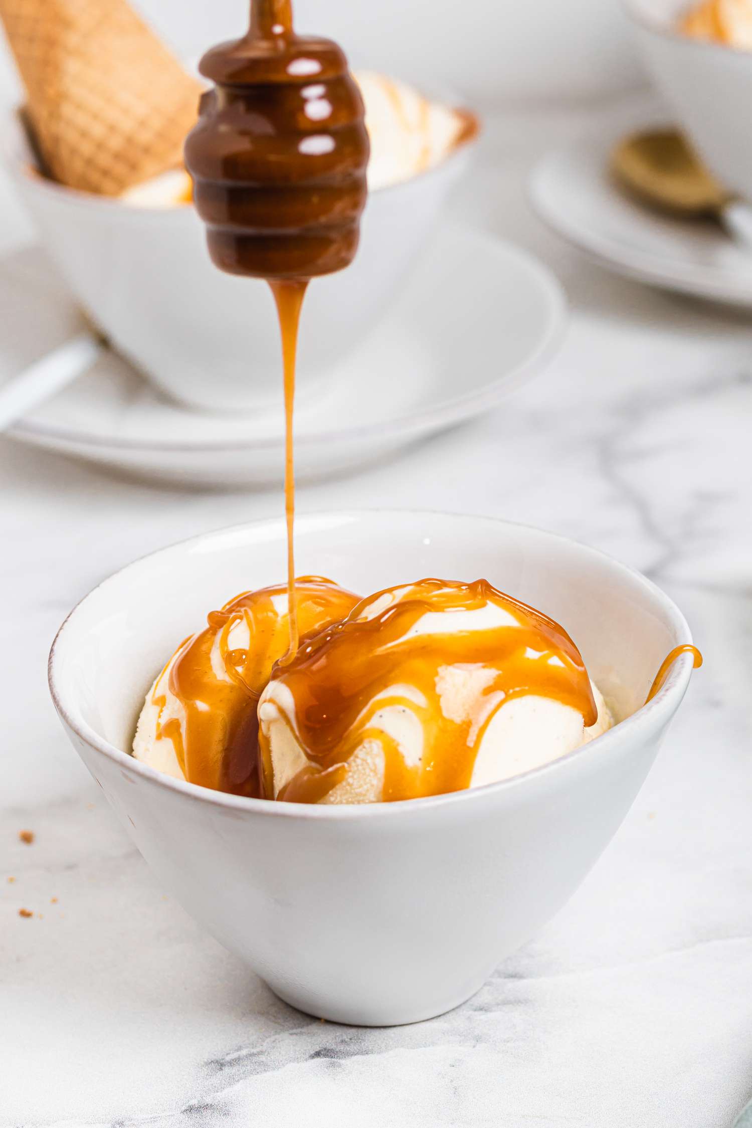 Drizzling caramel over a bowl of best vanilla ice cream.