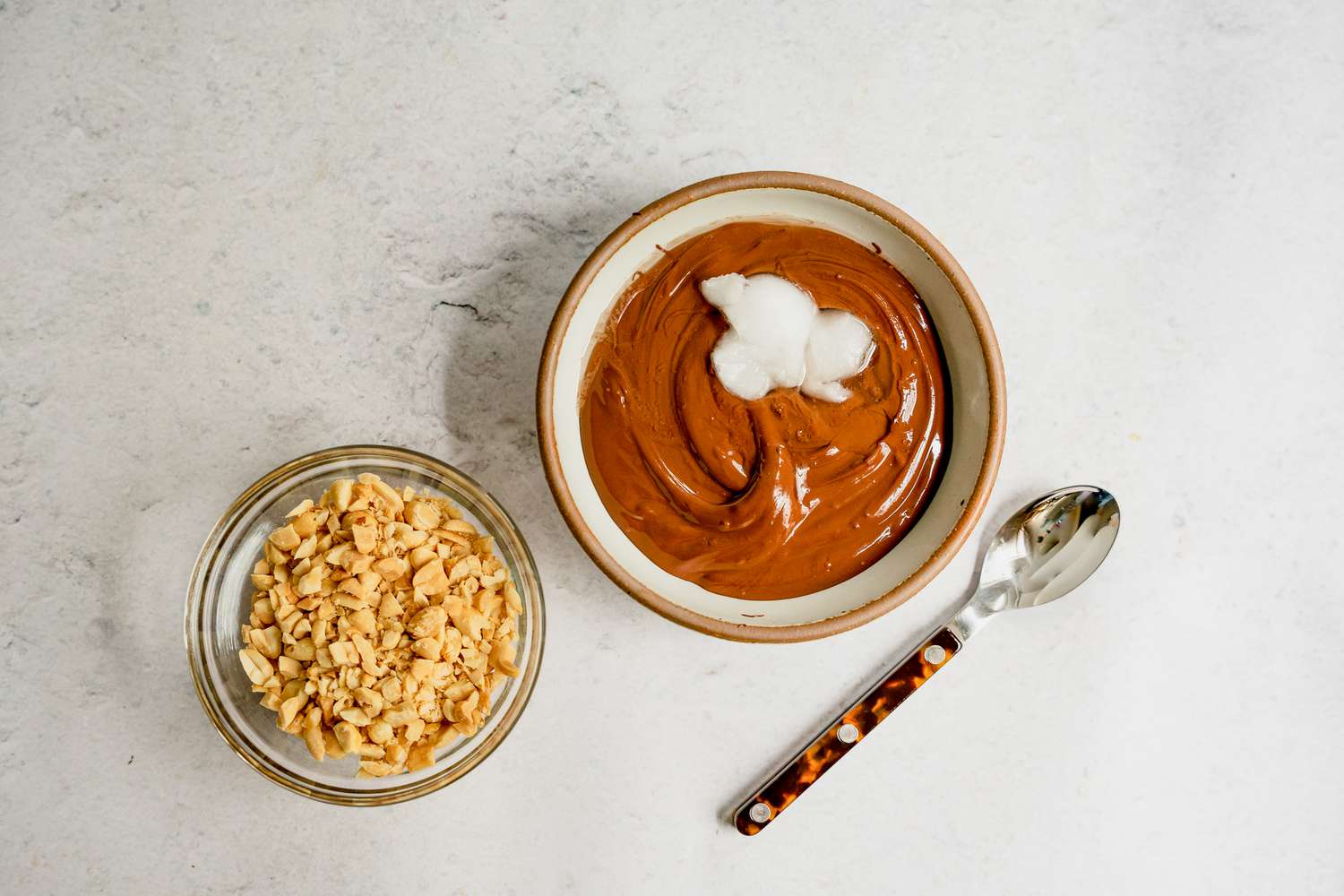 Melted chocolate with coconut oil and chopped peanuts in a bowl.