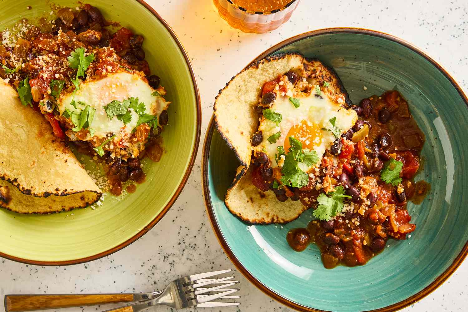 Two bowls with a serving of the black bean and egg bake recipe served with a corn tortilla, garnished with fresh cilantro
