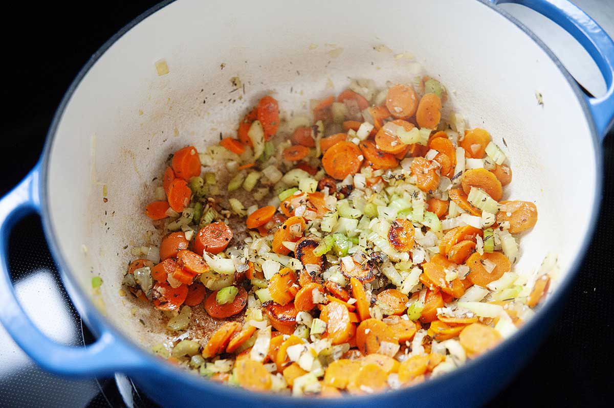 Carrots, onions and celery in the bottom of a dutch oven for easy to make homemade healthy creamy chicken noodle soup