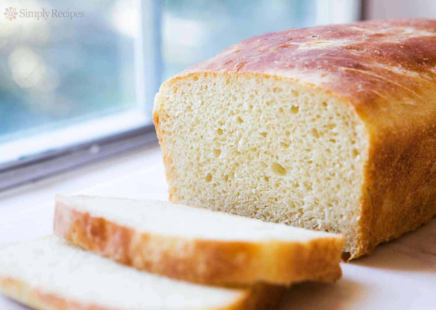 A loaf of sliced potato bread with a few slices on a cutting board