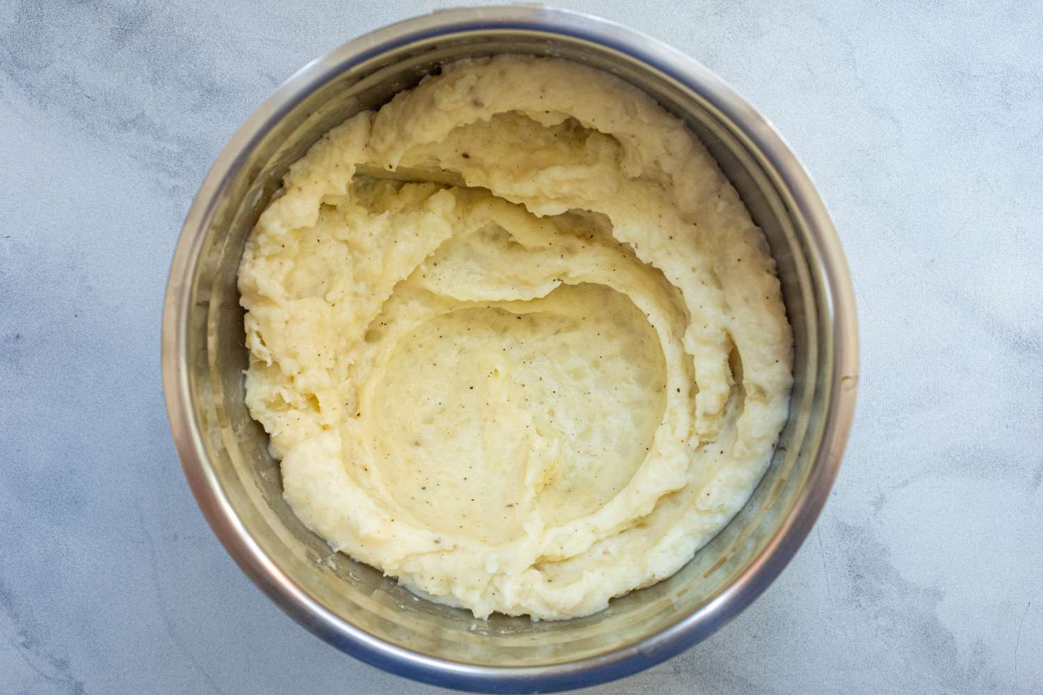Overhead view of mashed potatoes in a metal bowl to make cheesy leftover mashed potato pancakes.