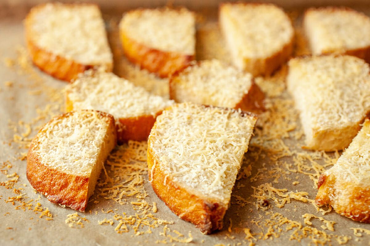Baguette slices of bread with shredded cheese sprinkled over the top of them 