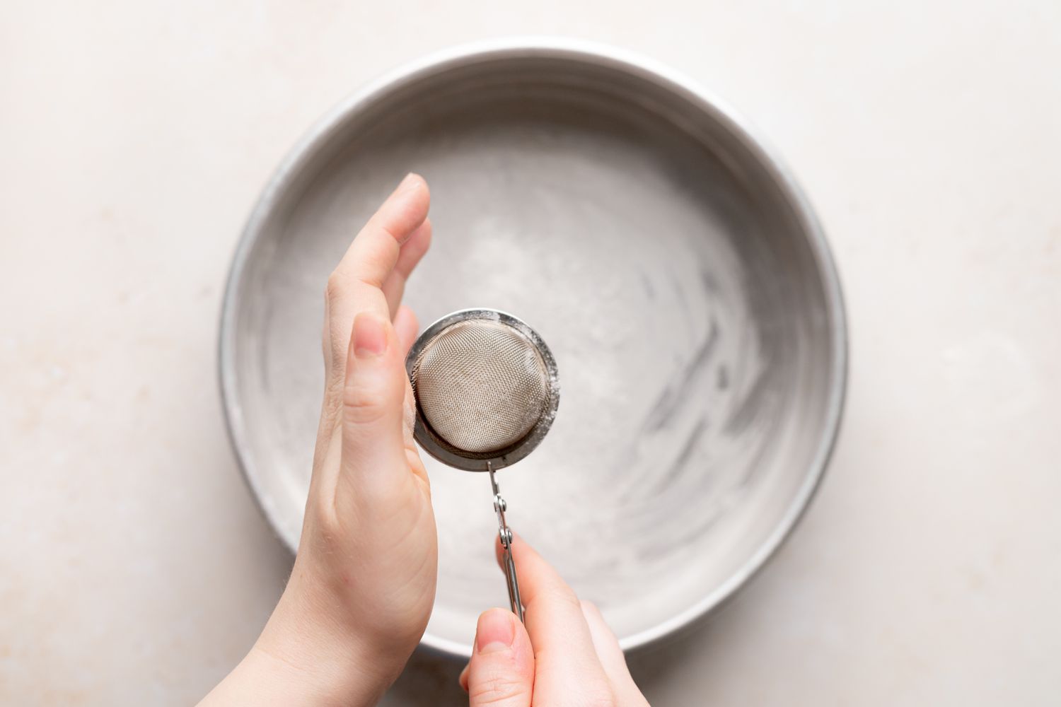 Flouring a cake pan to make a fresh cherry cake recipe.