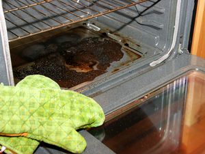 A dirty oven with oven mitts in the forefront