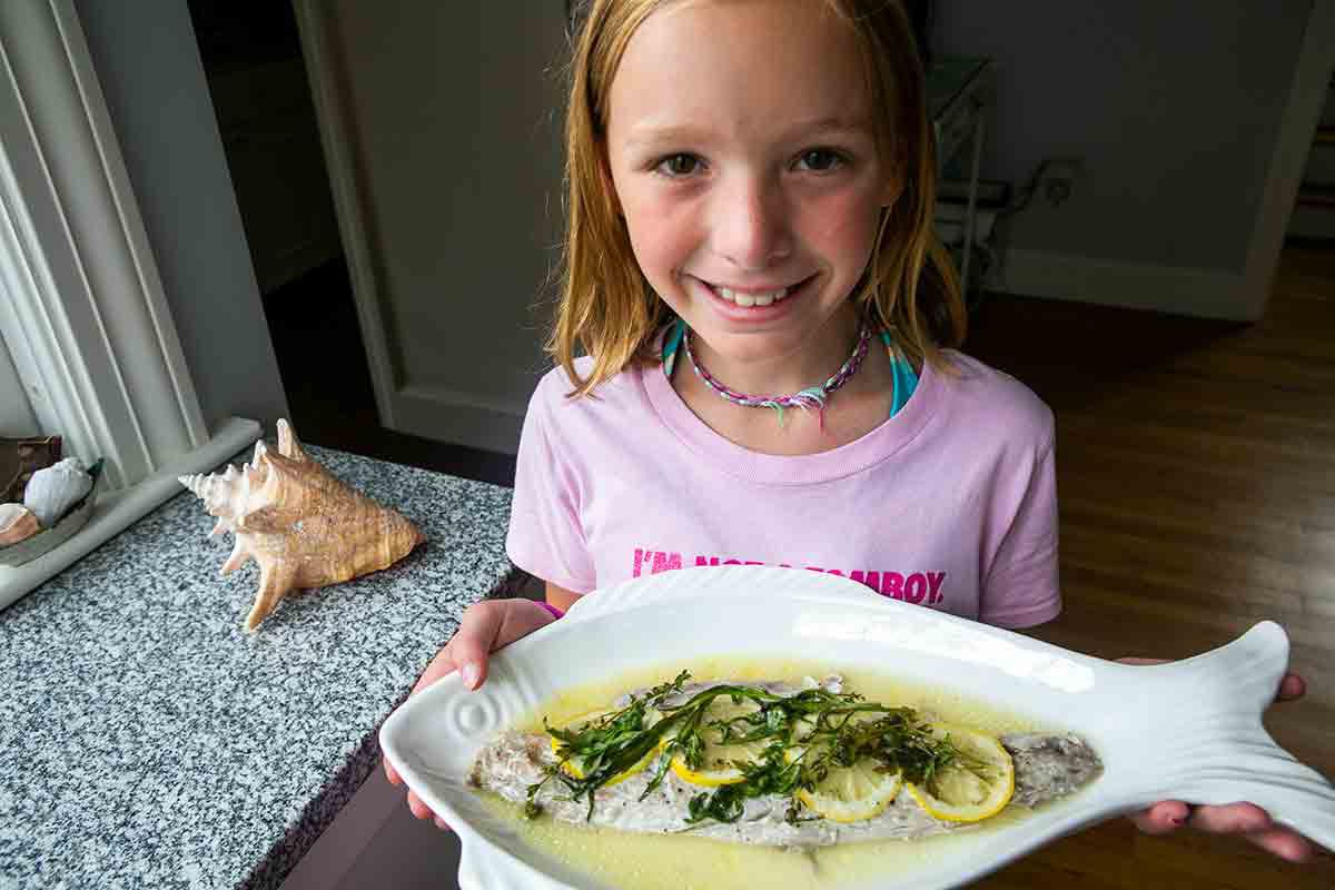 girl holding platter with cooked bluefish