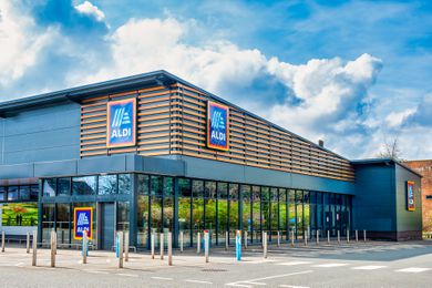 An exterior view of an Aldi supermarket building with a parking area in front