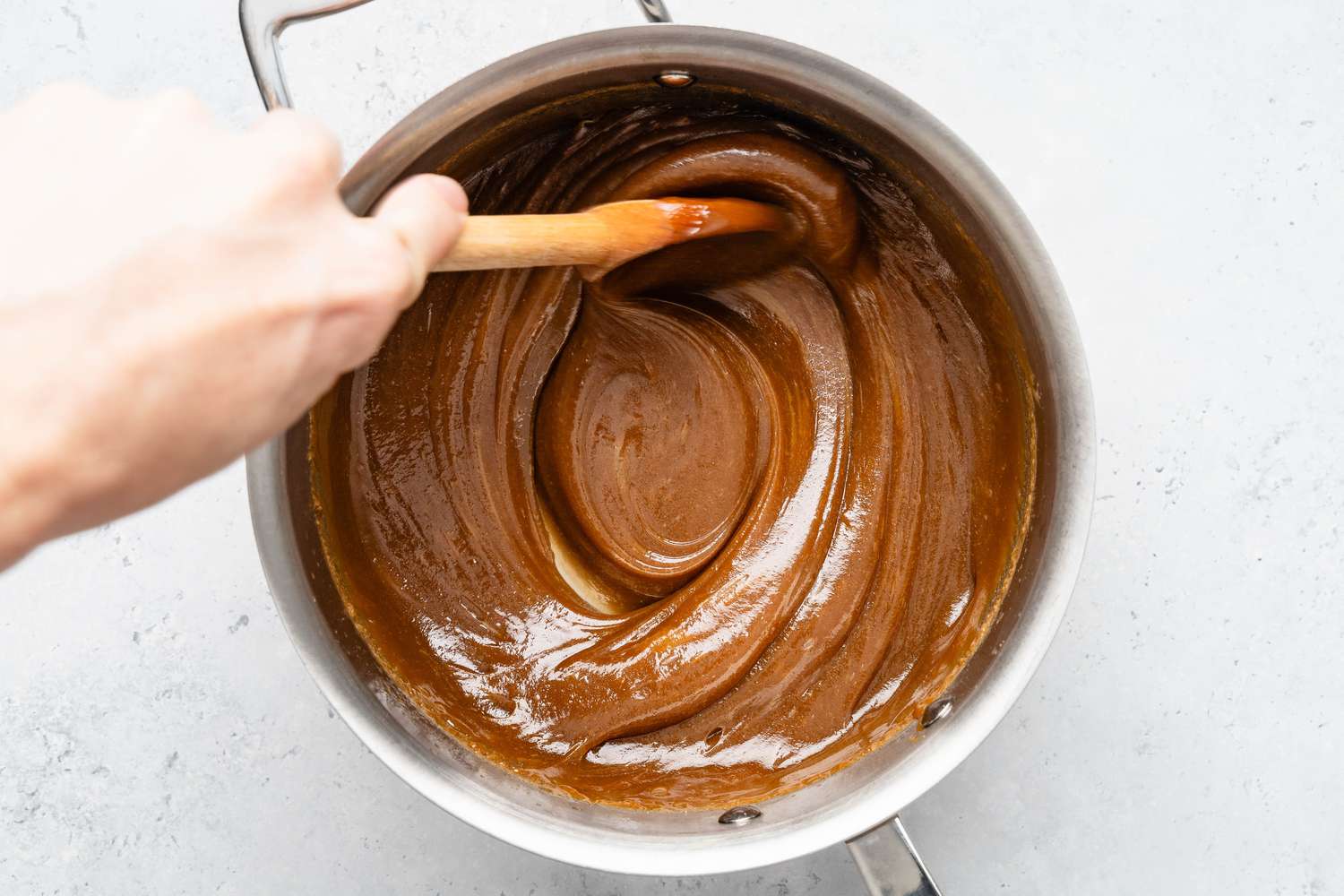 Cooled penuche mixture stirred using a wooden spoon