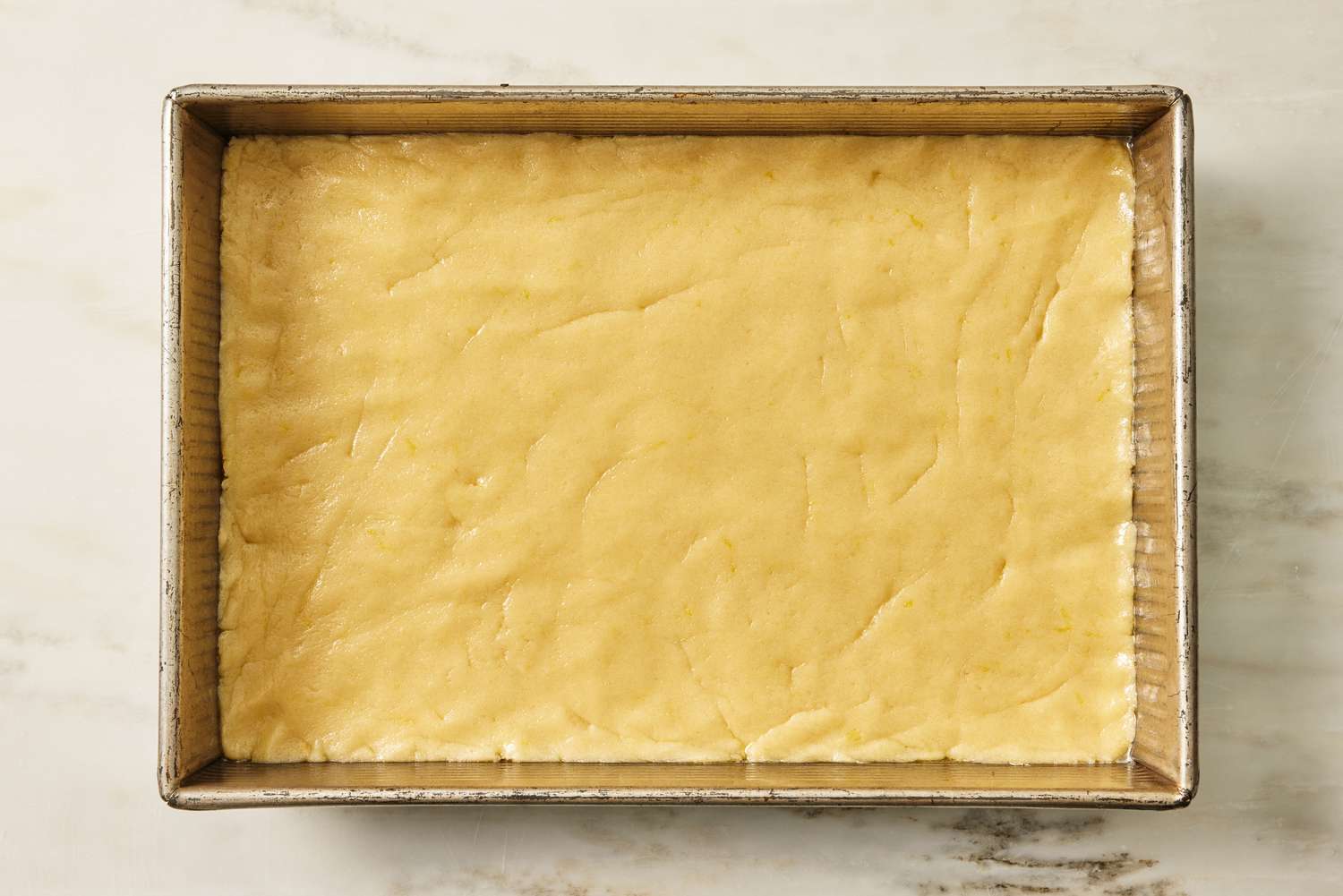 cake batter spread out into a large baking pan for Lemon Gooey Butter Cake recipe