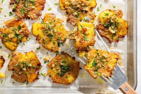 Roasted smashed potatoes with garlic and garnish on a tray