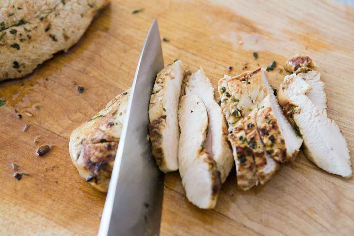 Chicken being sliced on a cutting board