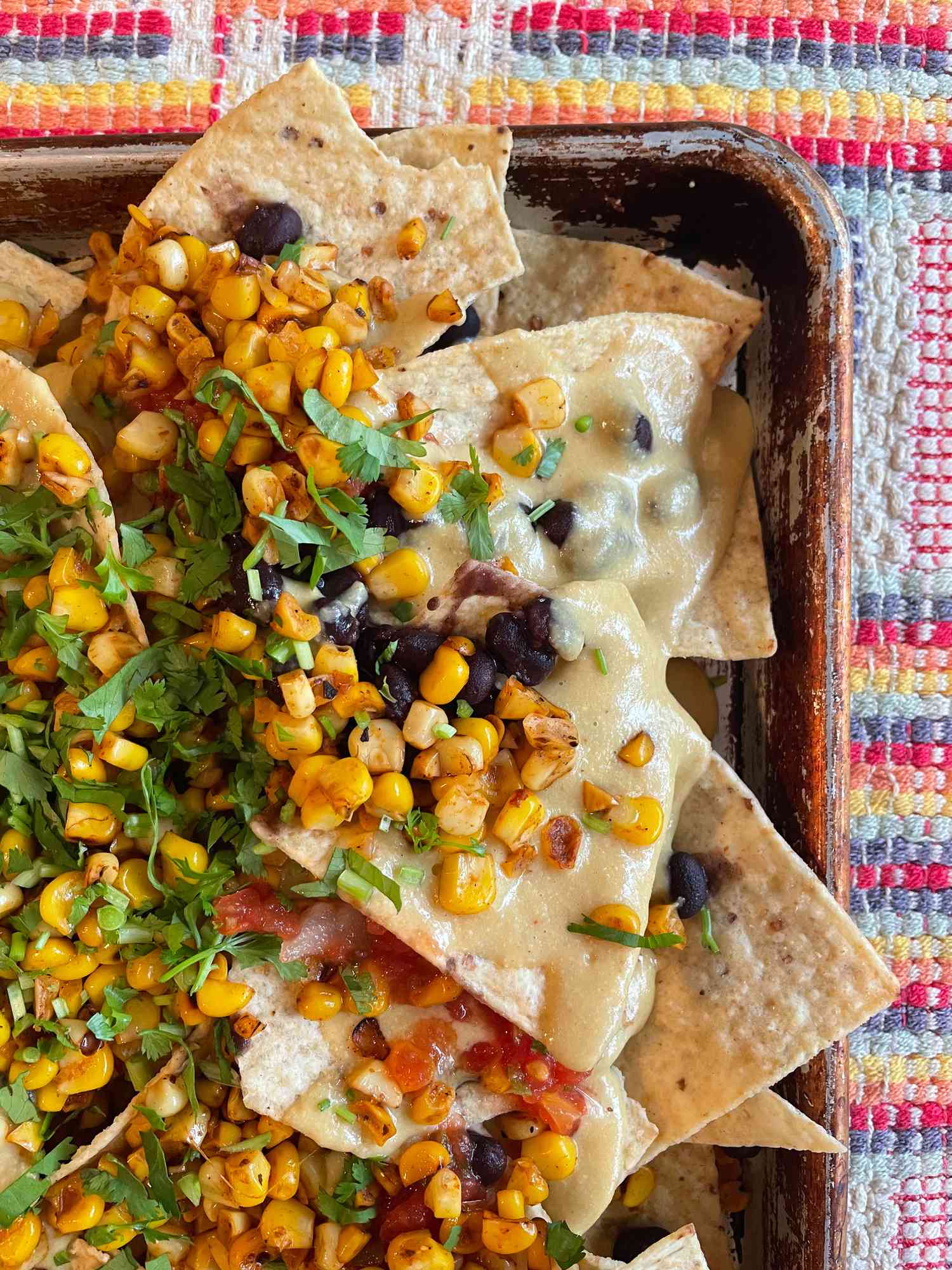 A close-up of Mexican street corn nachos (elote nachos) on a sheet pan