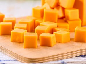 Cubes of cheddar cheese on a wooden cutting board