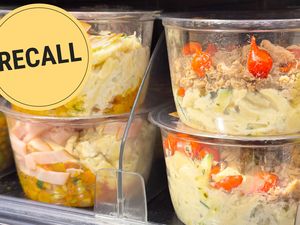 Packaged pasta salad in containers displayed in a refrigerator with a Recall label overlay
