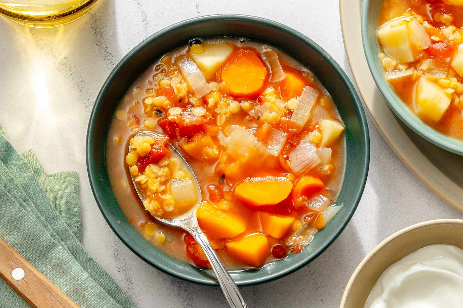 A bowl of slowcooked red lentil soup with vegetables and a spoon