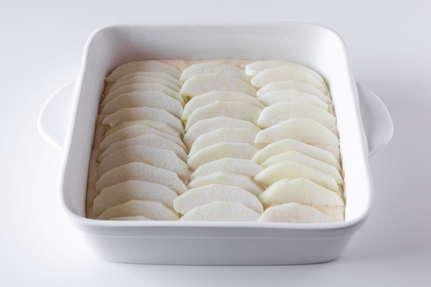 Sliced apples on top of bisquick batter to make a bisquick apple cobbler.