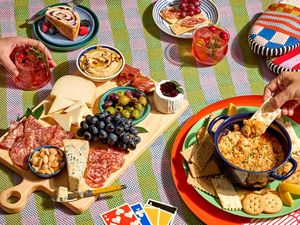 Table setting with charcuterie cheese plates dip and drinks accompanied by a card game