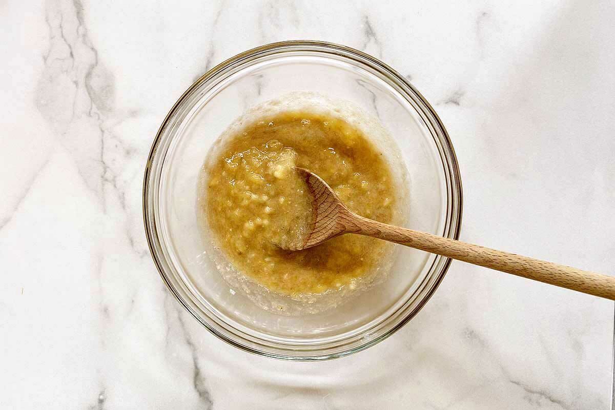 Mashed banana in a glass bowl for easy gluten free banana bread.