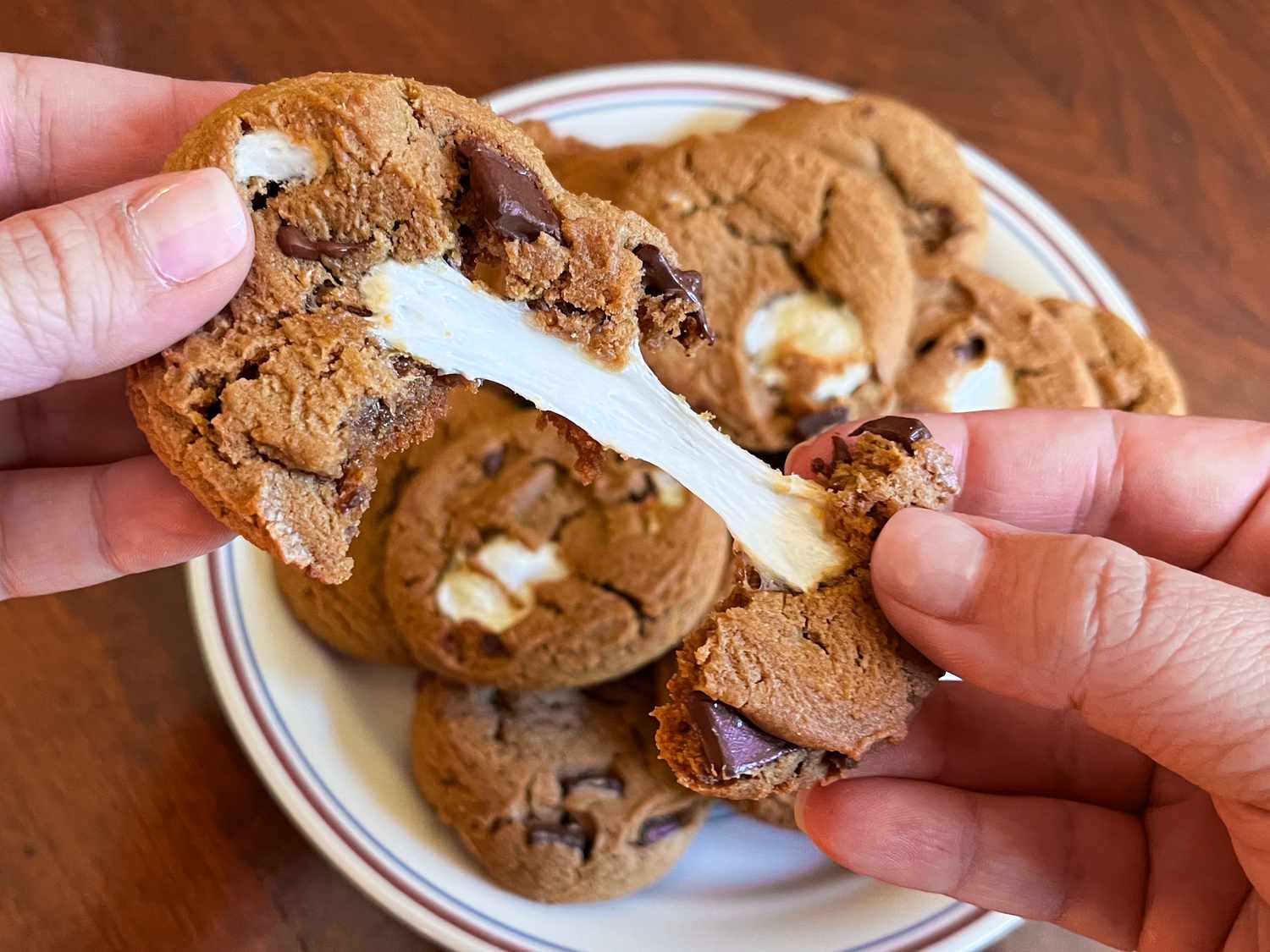someone pulling apart a s'mores cooking resulting in a delicous marshmallow pull 