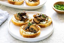 Three crostini topped with savory mushrooms and caramelized onions on a white plate.