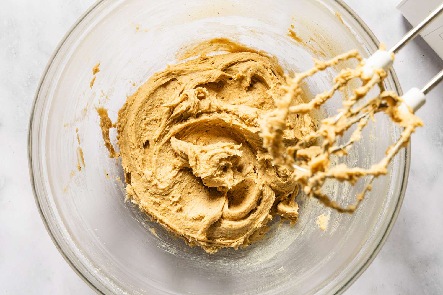 Dough being mixed in a glass bowl with an electric mixer