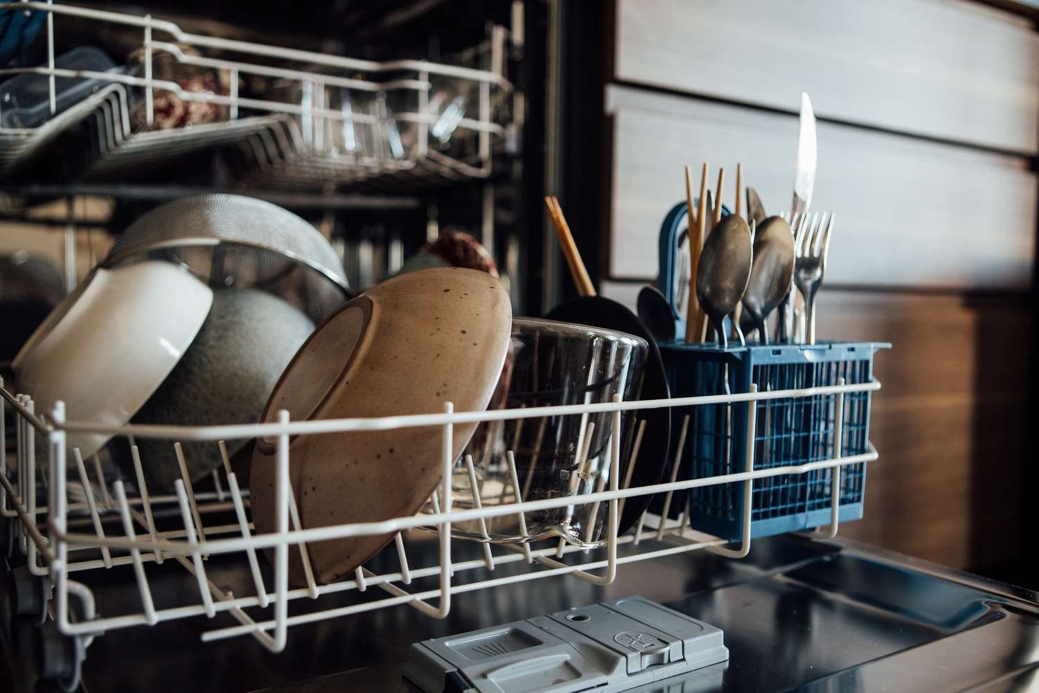 A dishwasher filled with bowls, plates, glasses, and silverware. 