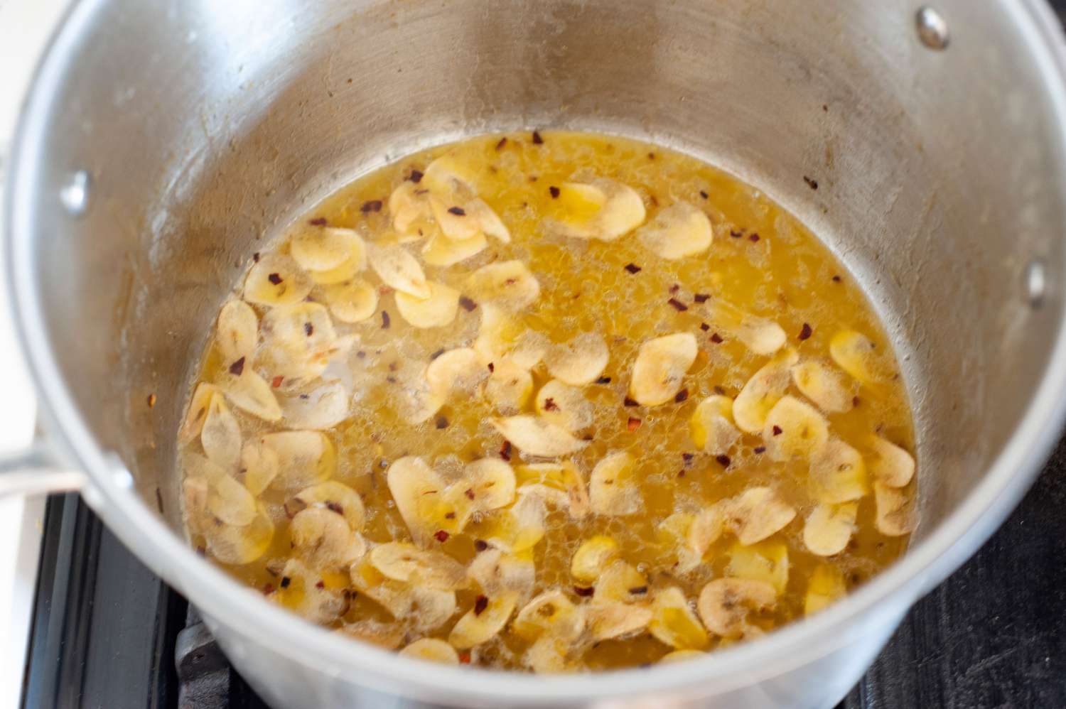 Olive Oil, Garlic, and Pepper Flakes Sizzling in a Pot for Spaghetti Aglio e Olio Recipe