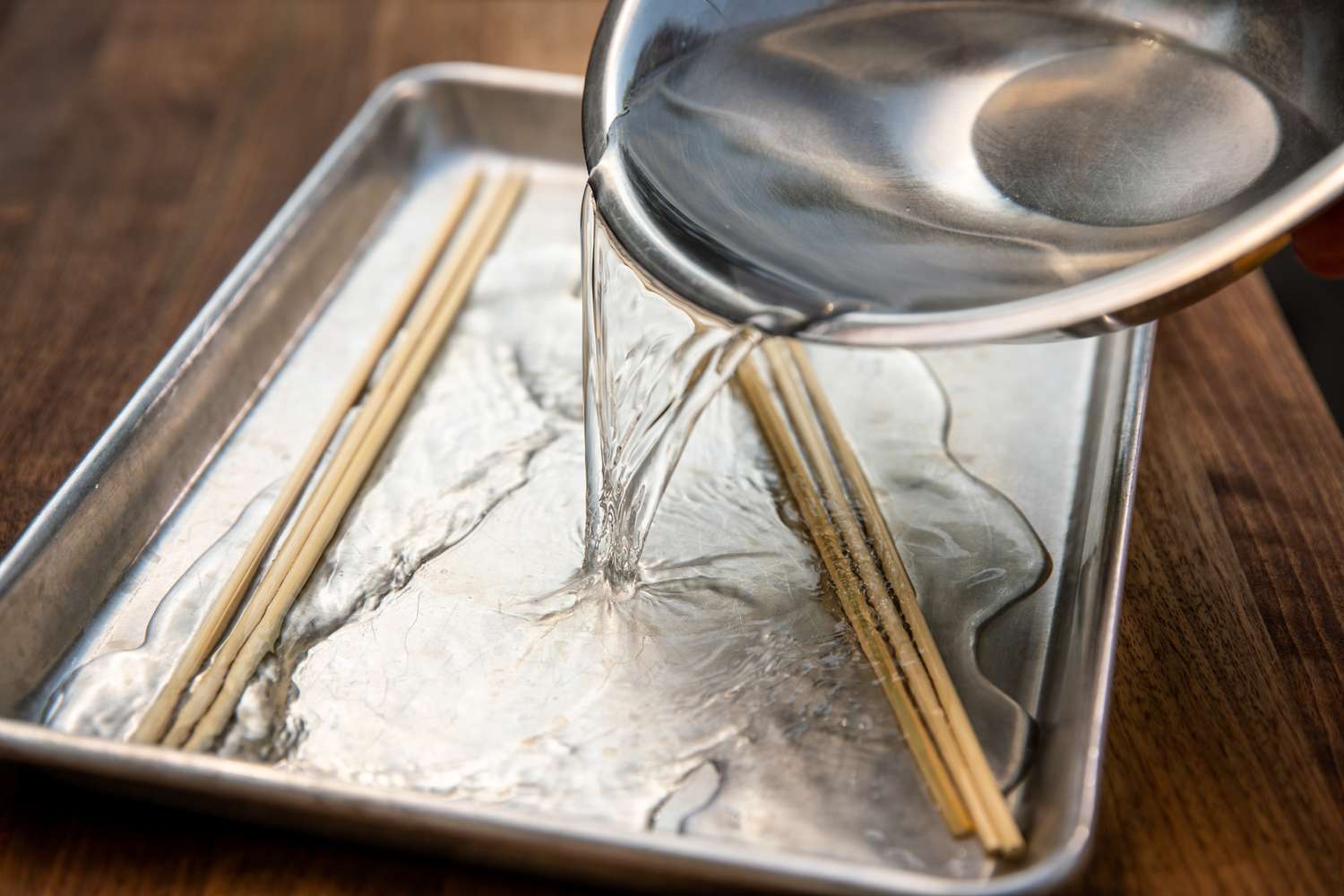 Bowl of Water Poured into a Sheet Pan with Skewers for Grilled Okra
