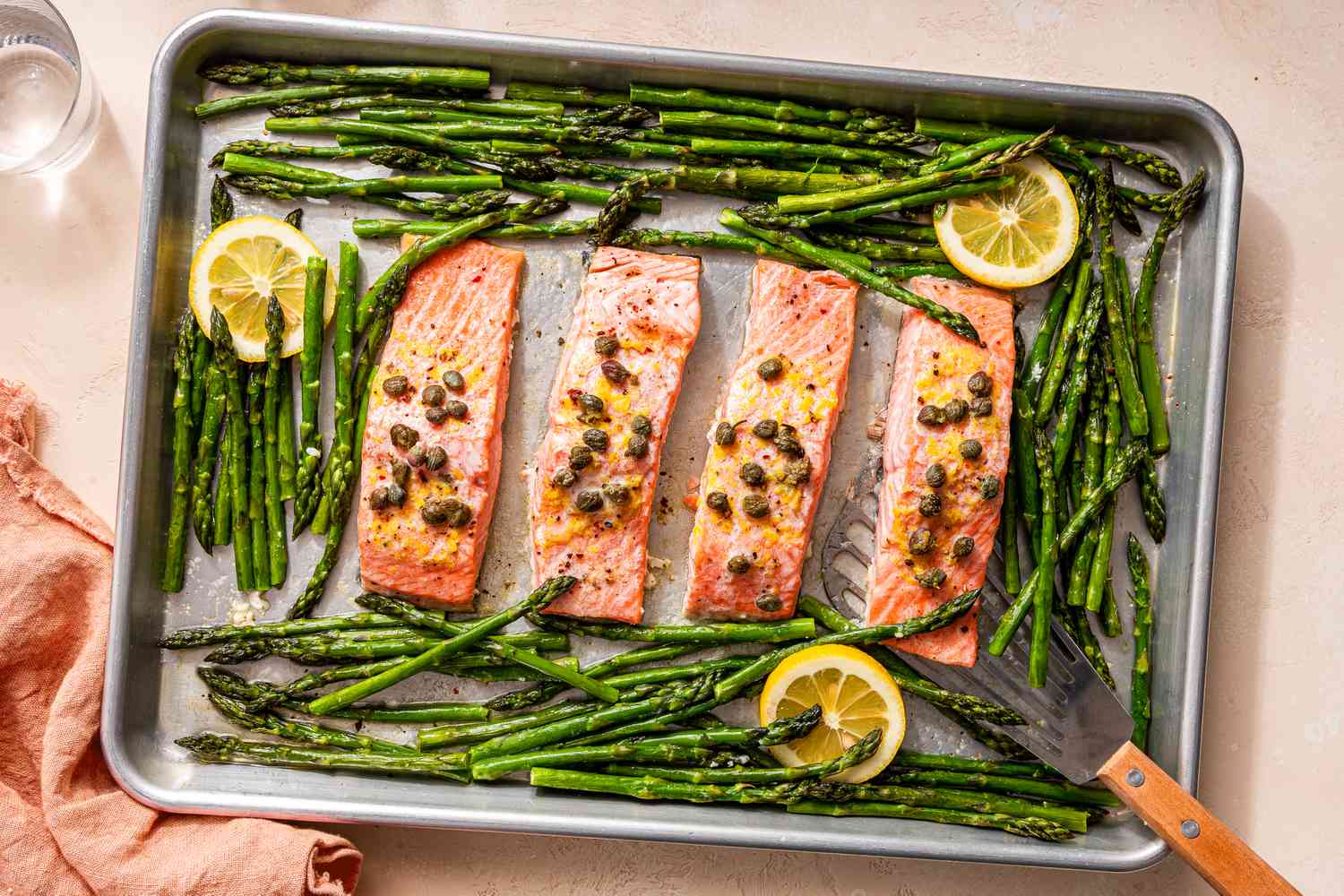 sheet pan salmon topped with lemon and capers next to asparagus