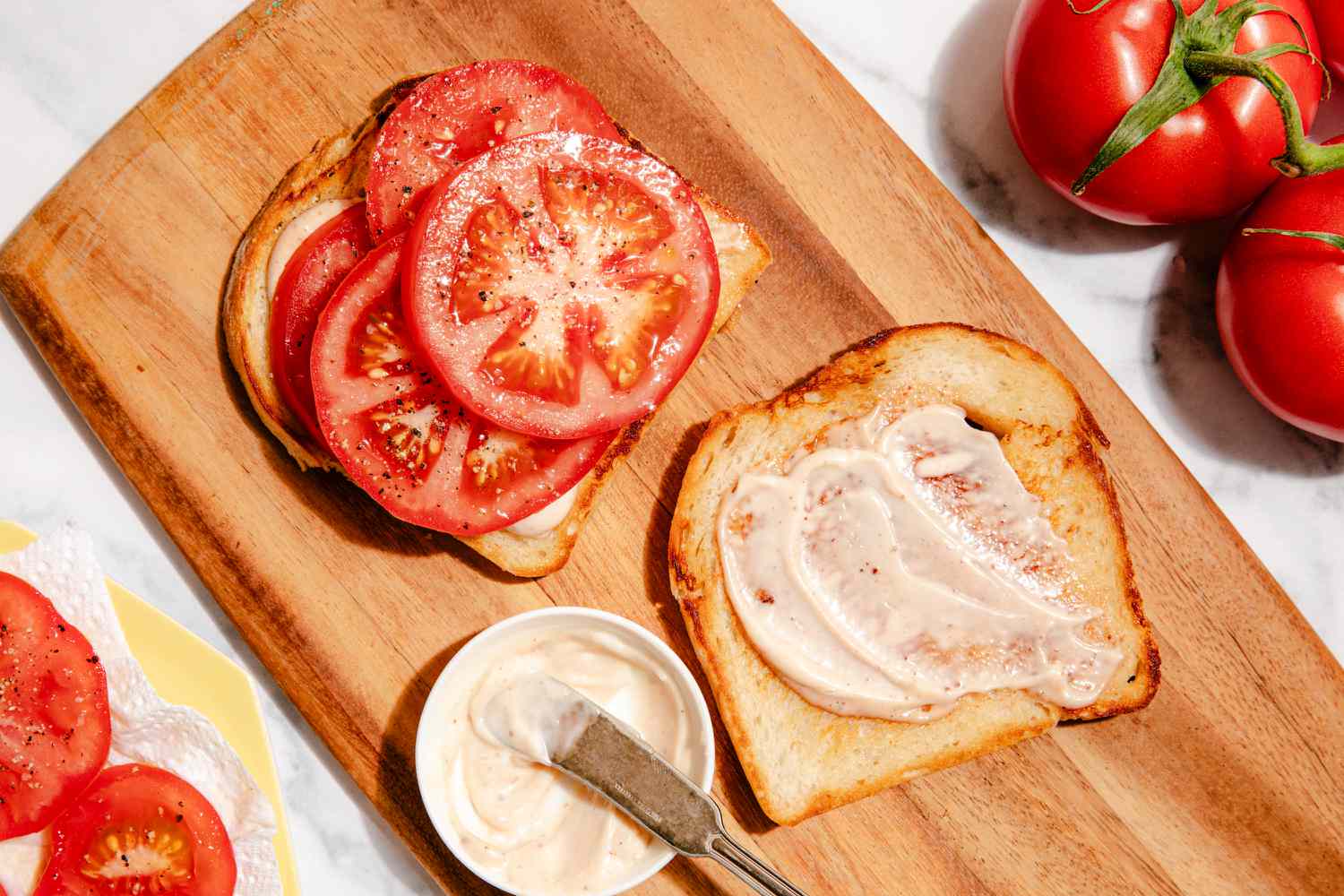 tomato sandwich being assembled on a cutting board 