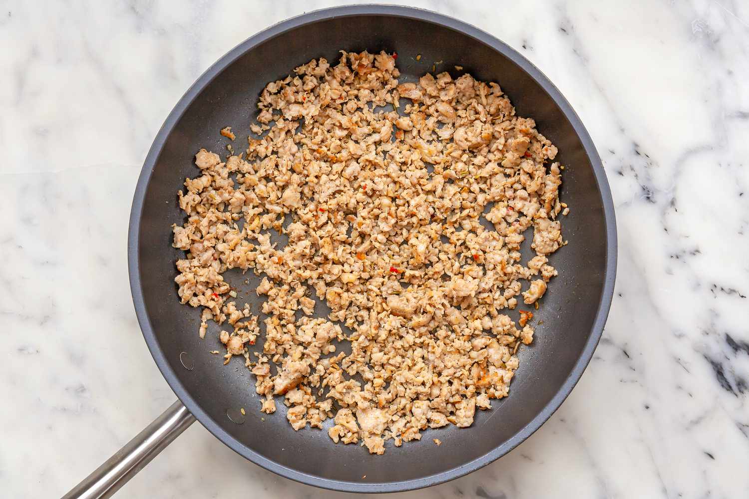 Sausage cooking in a skillet to make Chicago-Style Deep Dish Pizza.