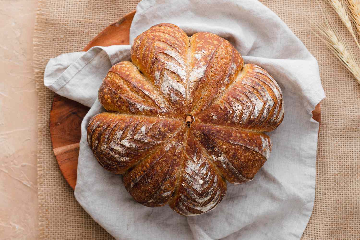 Overhead view of spiced pumpkin-shaped sourdough on a grey linen.