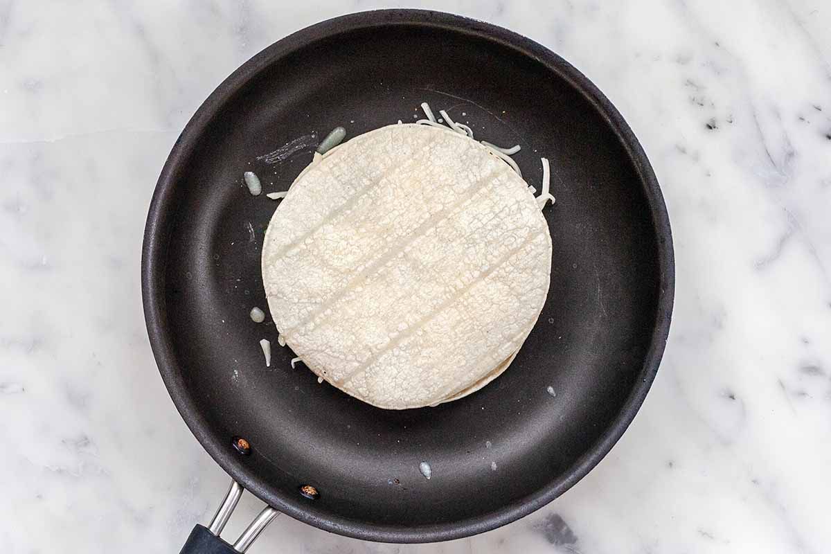 How to Make a Cheese Quesadilla with Mushrooms - uncooked tortillas filled iwth cheese in mushrooms in black skillet