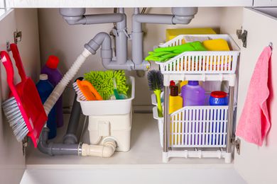 Cleaning tools and supplies in open cabinet under a kitchen sink