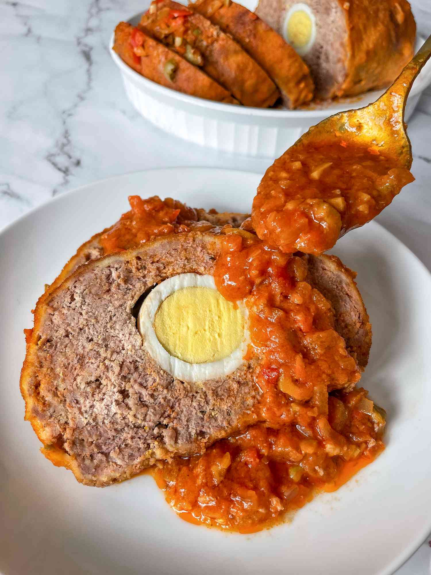 Pulpeta (Cuban Meatloaf) on a plate with sauced spooned over top.