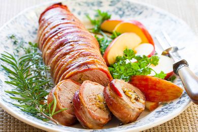 bacon wrapped pork loin served on platter with apples
