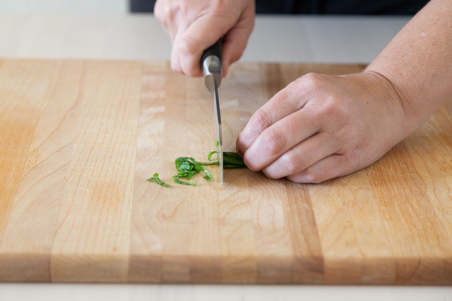 Slicing basil leaves into thin strips