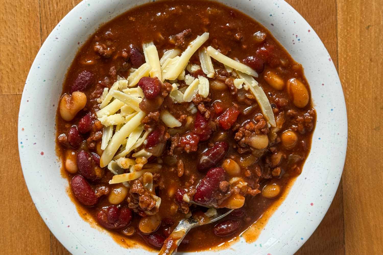Bowl of chili with shredded cheese on top and a spoon