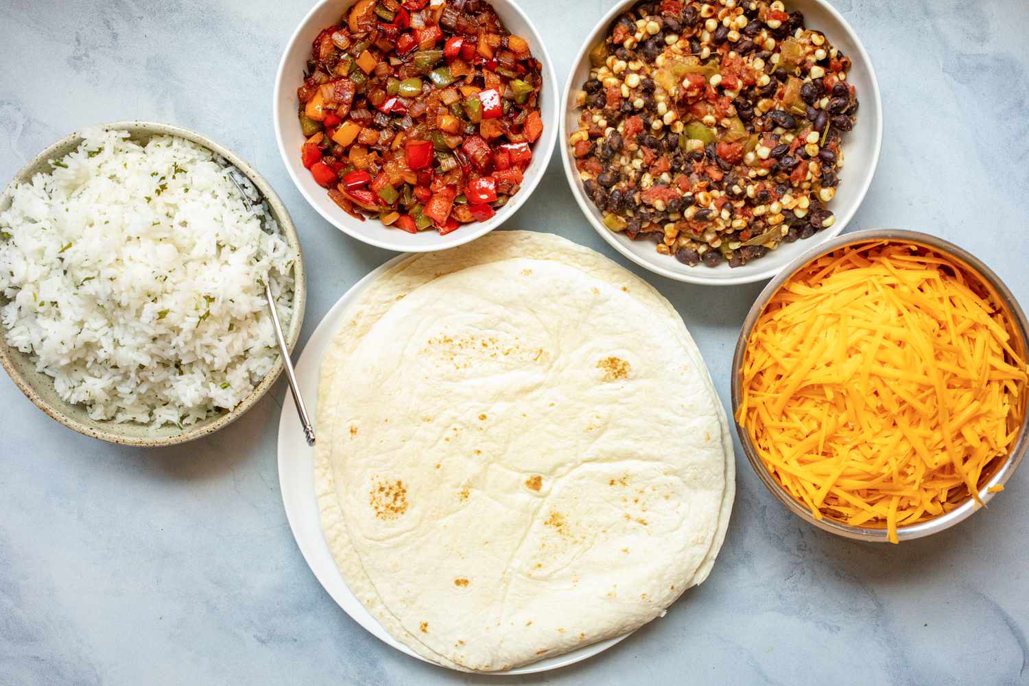 Tortillas, rice, cheese, black bean mixture, and peppers in bowls to make veggie burritos with beans, corn, and peppers.