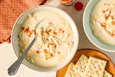 Bowls of creamy chicken mull soup with a spoon served with crackers